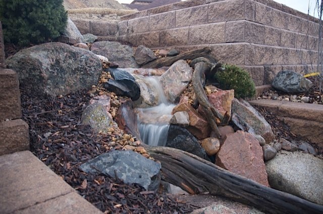 The backyard was was stark and barren before any landscaping was put in this Castle Rock, CO backyard. A pondless waterfall breaks through the retaining wall, adding life and sound! — in Castle Rock, CO.