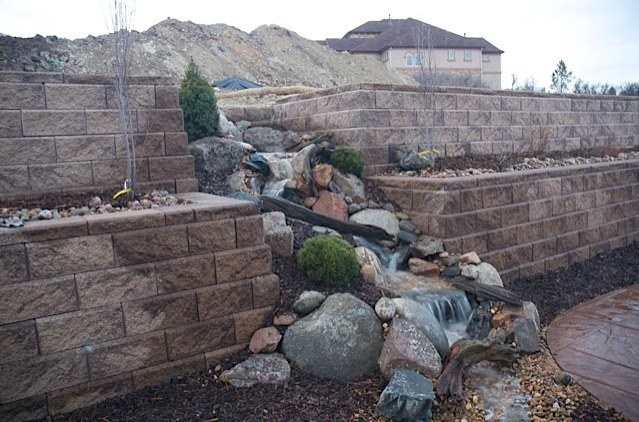 The backyard was was stark and barren before any landscaping was put in this Castle Rock, CO backyard. A pondless waterfall breaks through the retaining wall, adding life and sound! — in Castle Rock, CO.