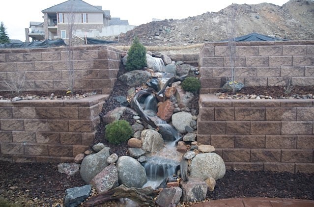 The backyard was was stark and barren before any landscaping was put in this Castle Rock, CO backyard. A pondless waterfall breaks through the retaining wall, adding life and sound! — in Castle Rock, CO.